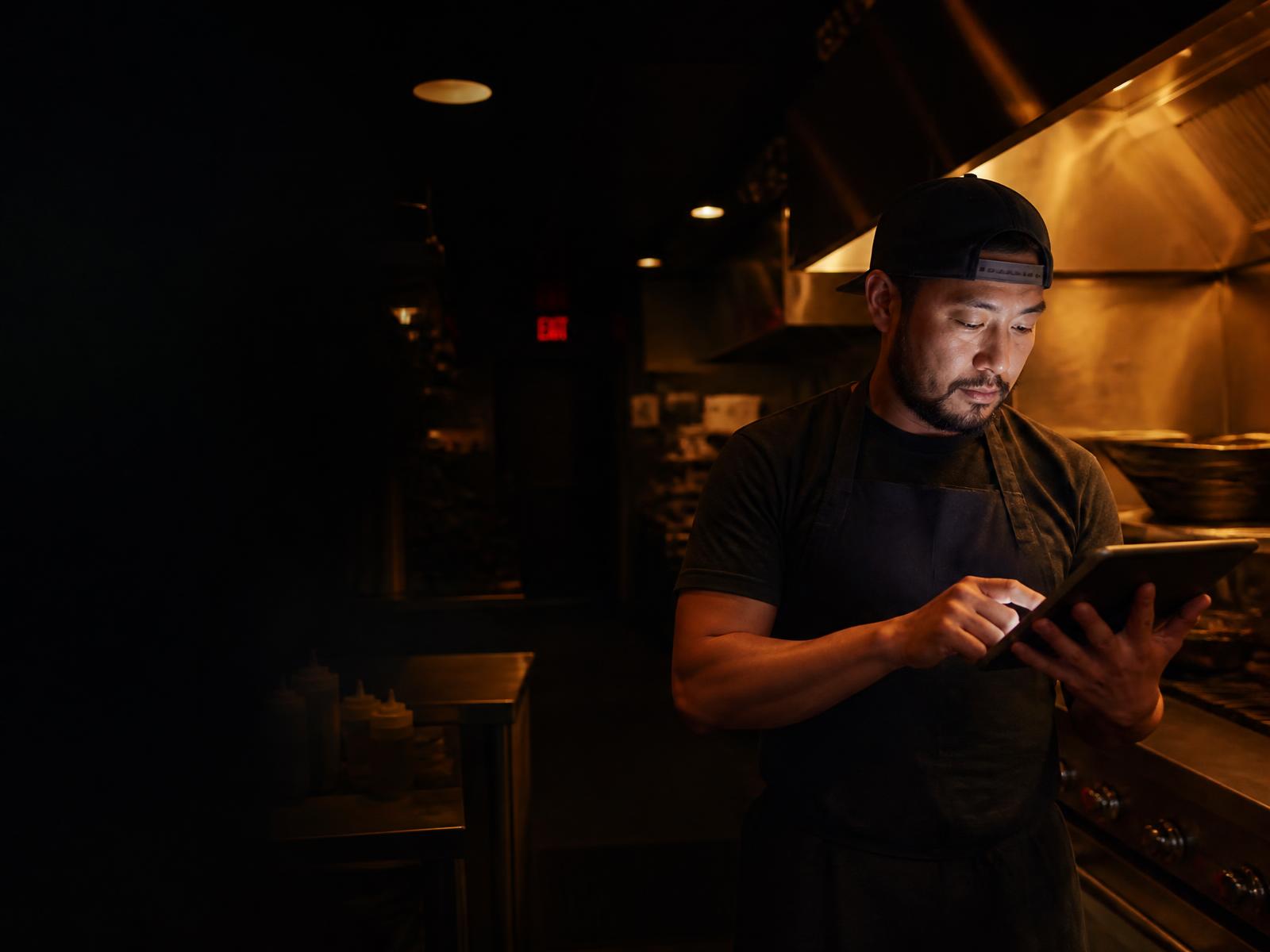 Proprietário acompanhando os números da operação dentro da cozinha do restaurante